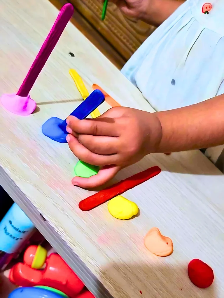 a toddler is sorting colors using popsicles and play-dough