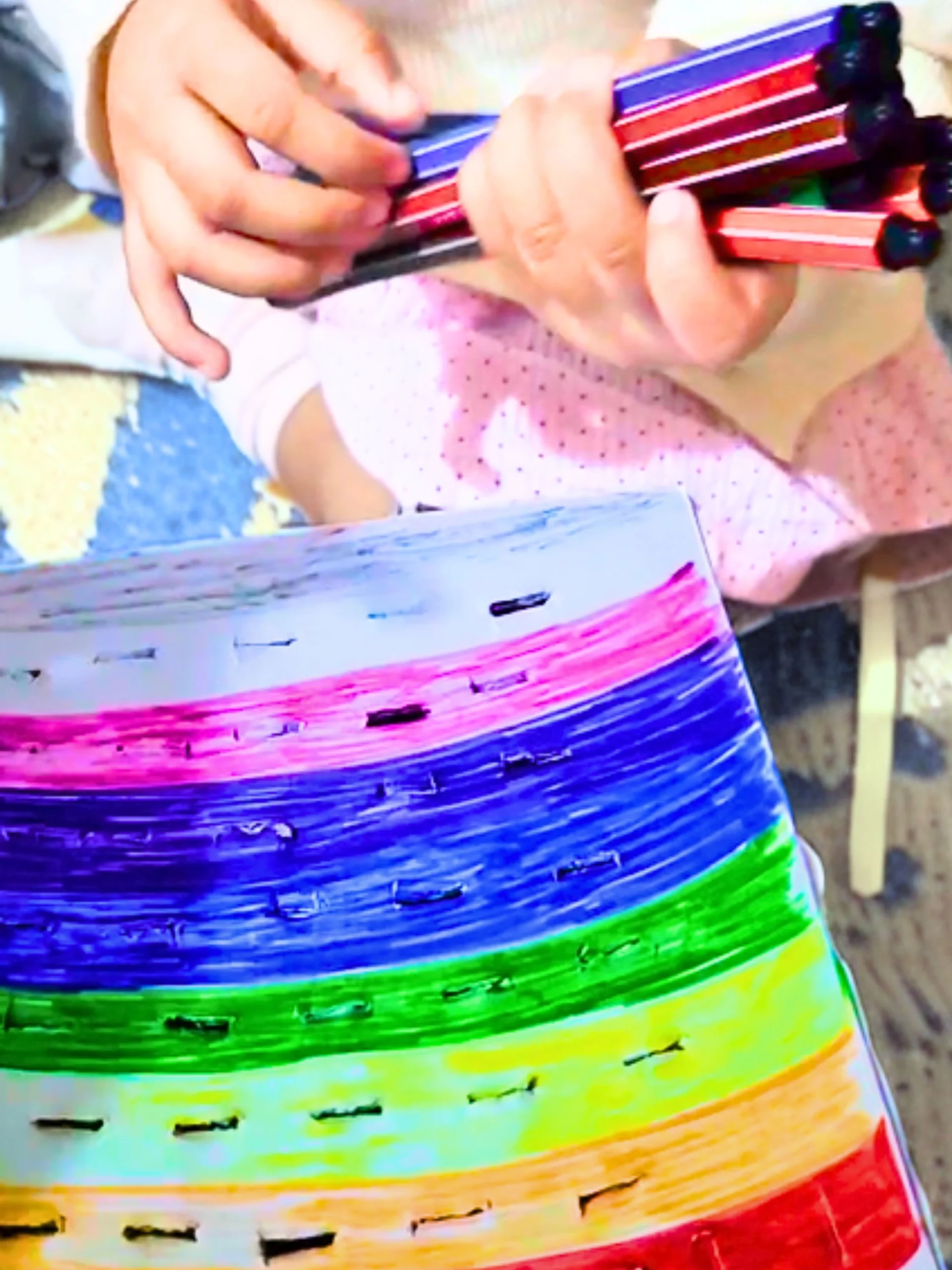 a toddler is sorting colors using color pens and a rainbow illustrated carboard box top