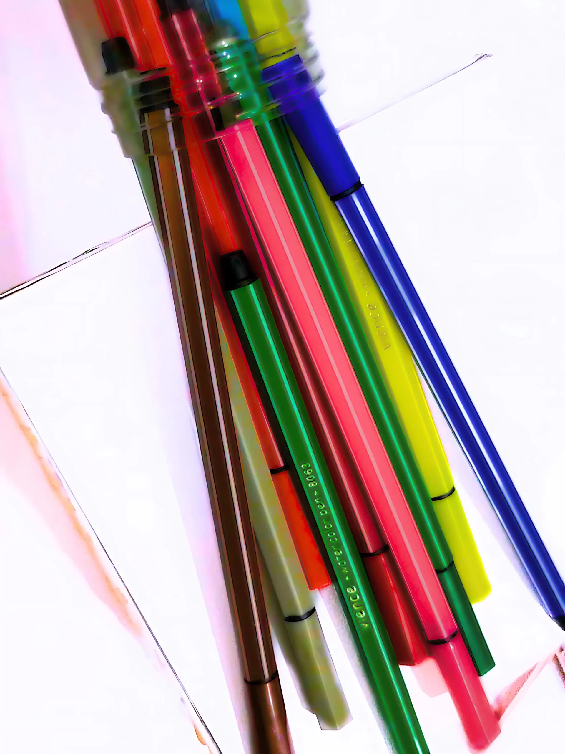 bunch of colored pens have been dropped on a white cardboard piece