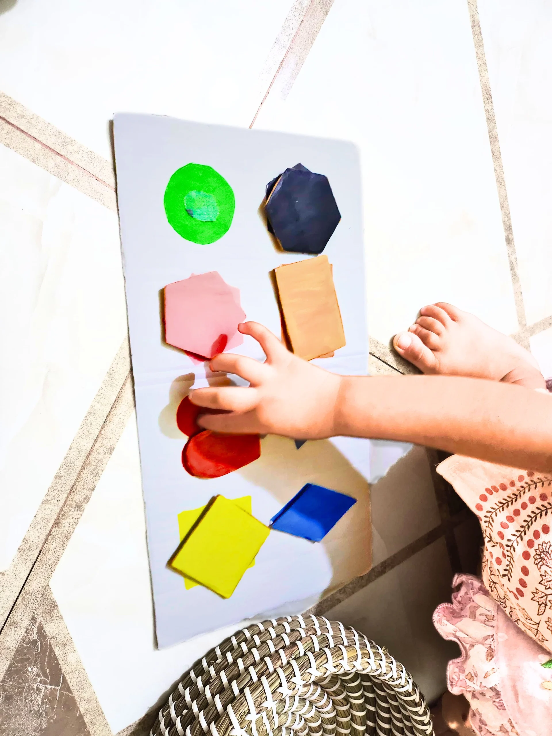 a toddler sorting shapes on a DIY cardboard shape sorter